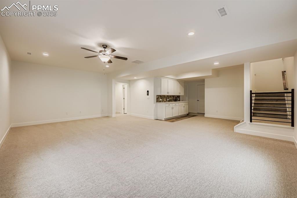 Image 23 of 28: Unfurnished living room with recessed lighting, light carpet, a ceiling fan