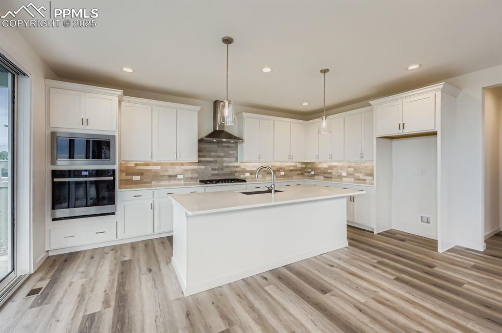 Image 7 of 28: Kitchen featuring white cabinets, stainless steel appliances, decorative ba