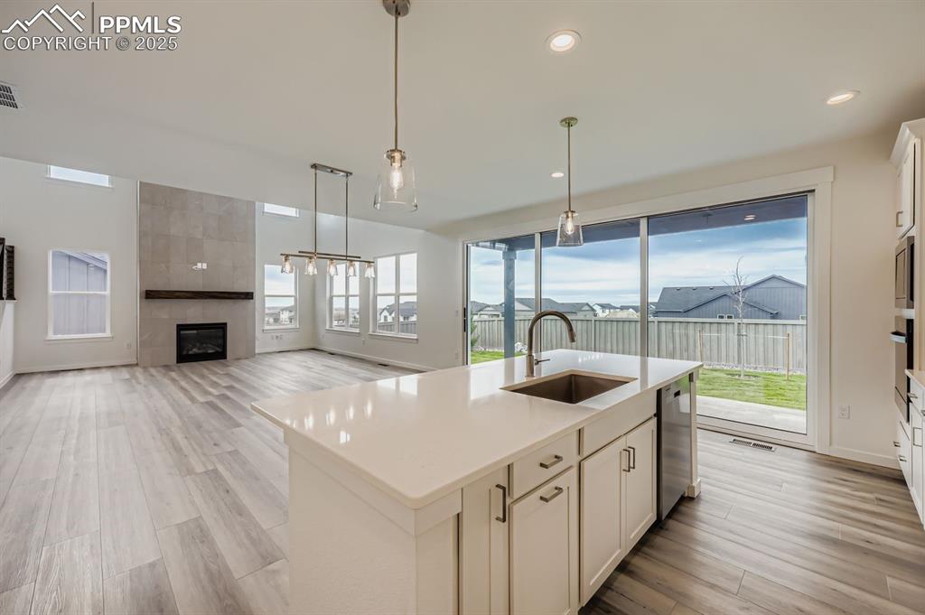 Image 9 of 28: Kitchen featuring white cabinetry, a kitchen island with sink, pendant ligh