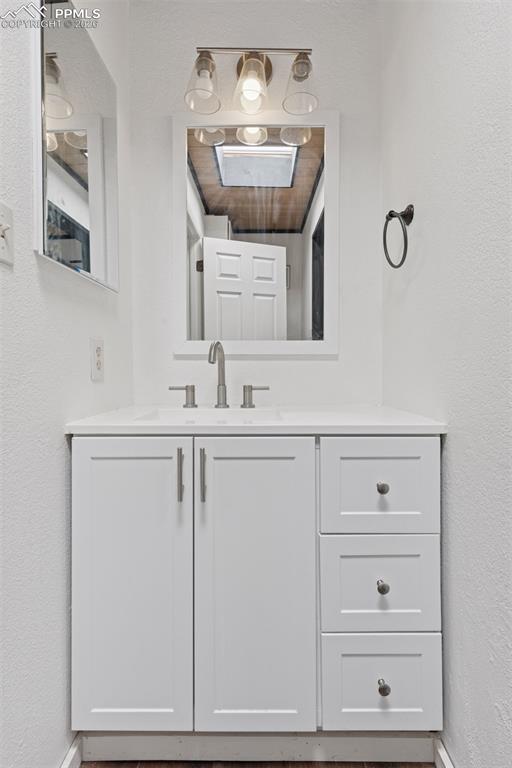 Image 19 of 49: Secondary bathroom with single-sink vanity, mirror, and overhead lighting (