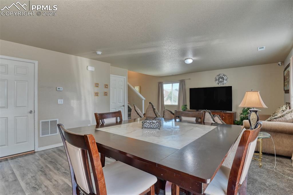 Image 17 of 43: Dining area featuring a textured ceiling, wood finished floors, and stairwa