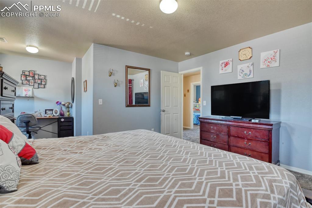 Image 29 of 43: Carpeted bedroom featuring a textured ceiling and baseboards