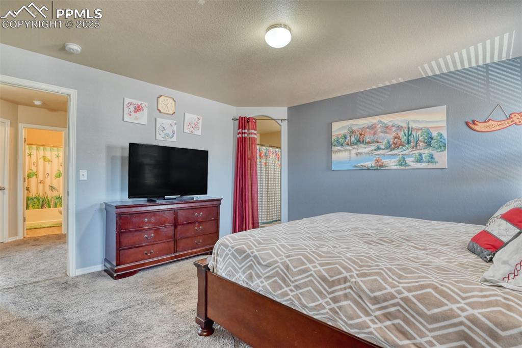 Image 30 of 43: Carpeted bedroom with a textured ceiling and baseboards