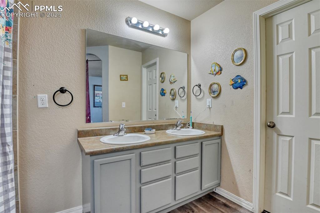 Image 32 of 43: Full bath featuring a textured wall, double vanity, and wood finished floor