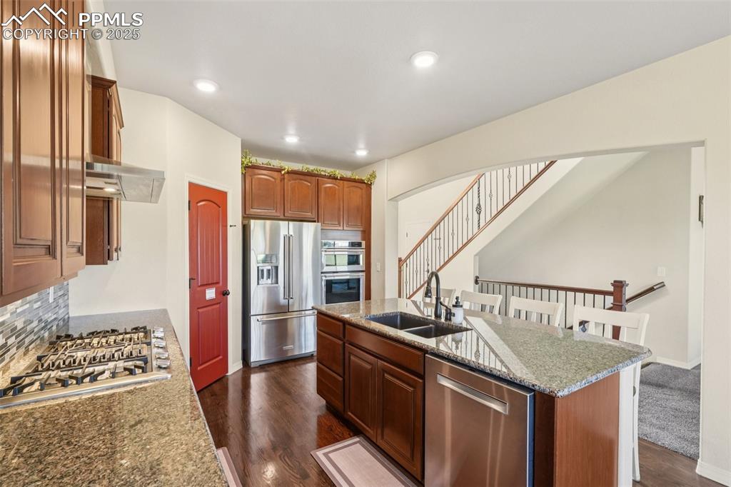 Image 10 of 46: Kitchen featuring appliances with stainless steel finishes, dark wood finis