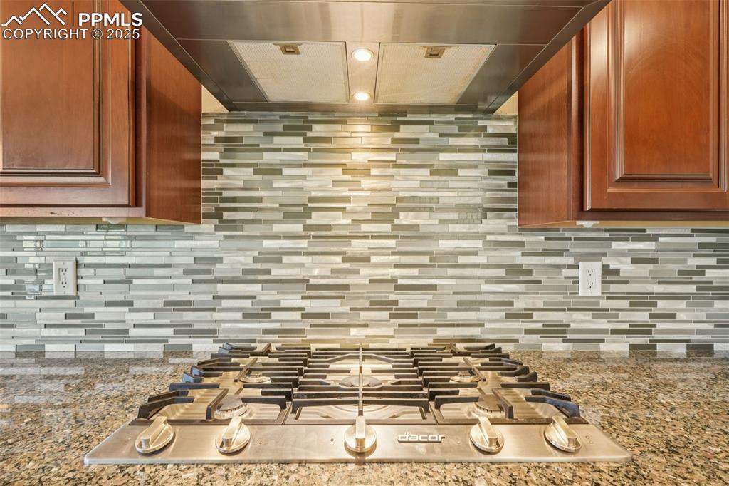 Image 11 of 46: Kitchen view of extractor fan, stainless steel gas cooktop, tasteful backsp