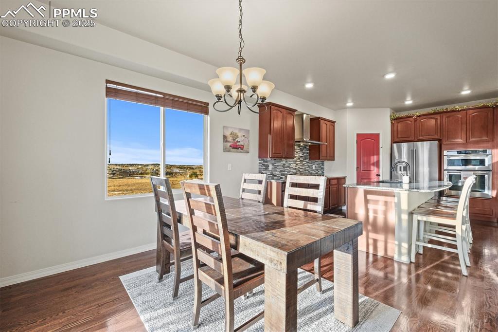 Image 13 of 46: Dining area featuring a chandelier, baseboards, dark wood finished floors,