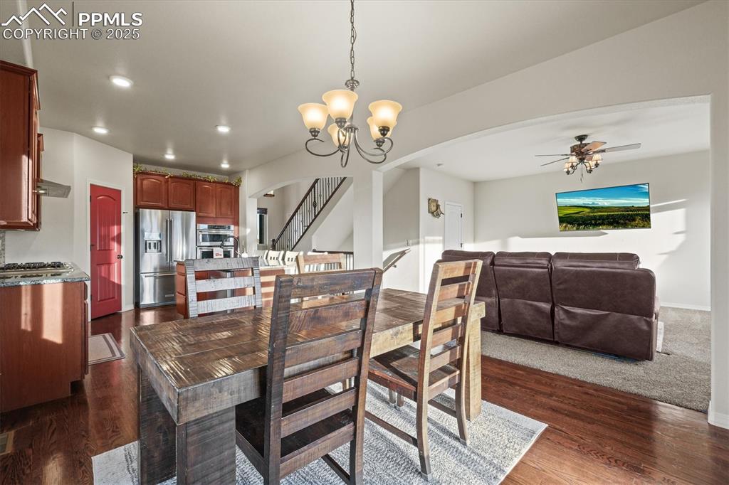 Image 14 of 46: Dining space featuring ceiling fan with notable chandelier, arched walkways