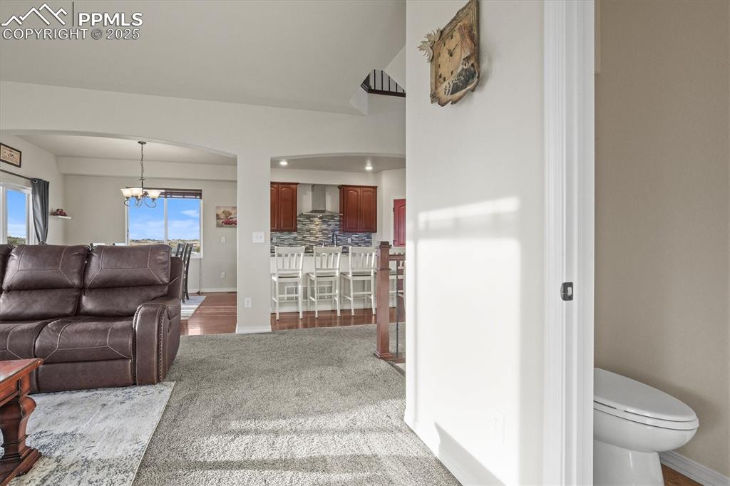 Image 16 of 46: Living room featuring an inviting chandelier, baseboards, and arched walkwa