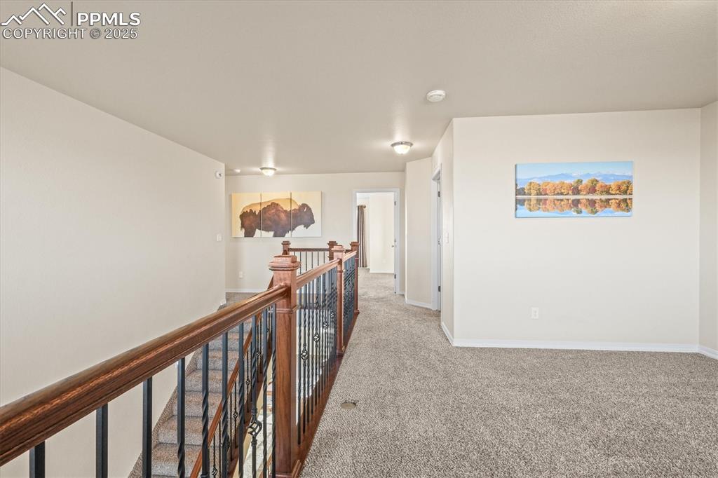Image 19 of 46: Hallway featuring carpet, baseboards, and an upstairs landing