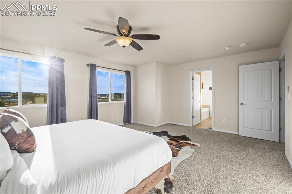 Image 23 of 46: Bedroom with carpet, baseboards, ceiling fan, and connected bathroom