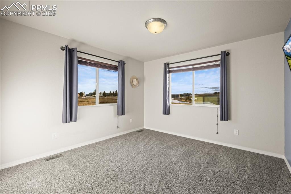 Image 28 of 46: Unfurnished room with baseboards, dark carpet, visible vents, and a healthy