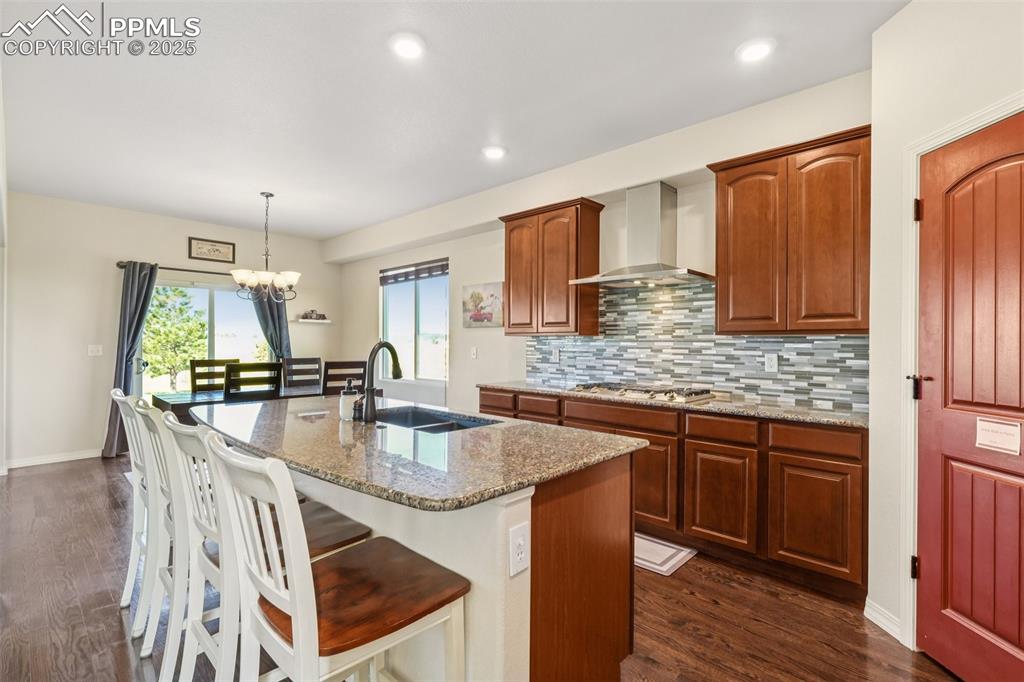 Image 3 of 46: Kitchen featuring an island with sink, wall chimney exhaust hood, light sto