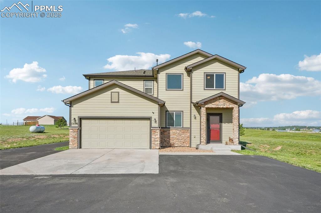 Image 9 of 46: View of front of property featuring concrete driveway, stone siding, and a