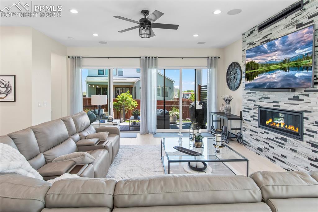 Image 10 of 48: Living room with a fireplace, ceiling fan, recessed lighting, and wood fini