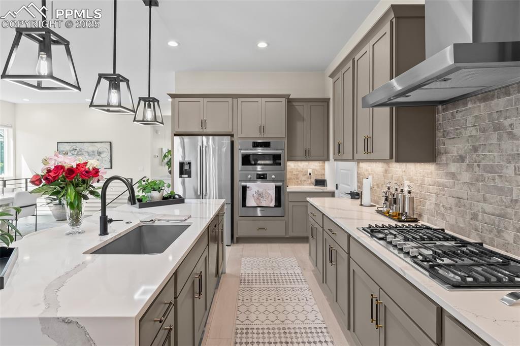 Image 16 of 48: Kitchen featuring decorative backsplash, wall chimney range hood, light sto