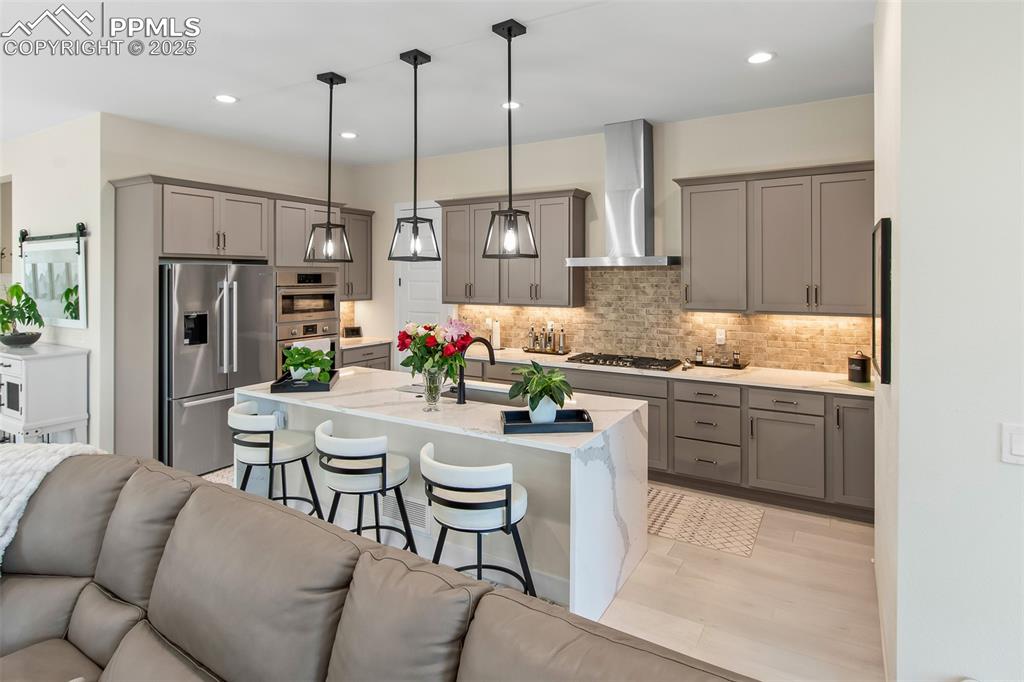 Image 19 of 48: Kitchen with open floor plan, gray cabinetry, light stone countertops, a br