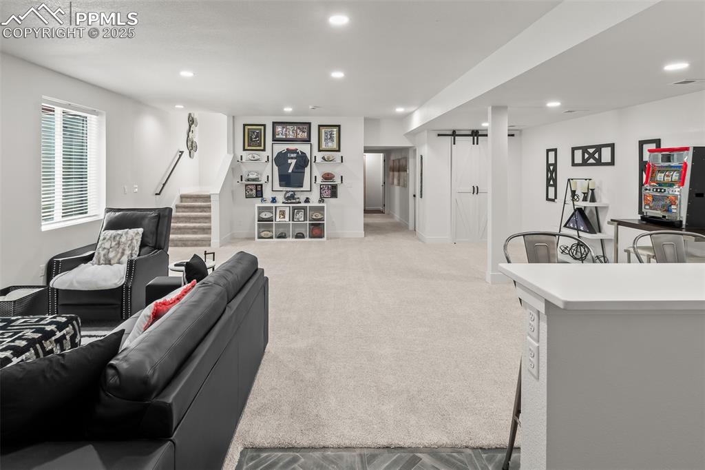 Image 36 of 48: Living area featuring a barn door, recessed lighting, light colored carpet,