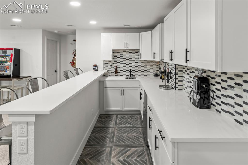 Image 39 of 48: Kitchen featuring tasteful backsplash, white cabinets, recessed lighting, a