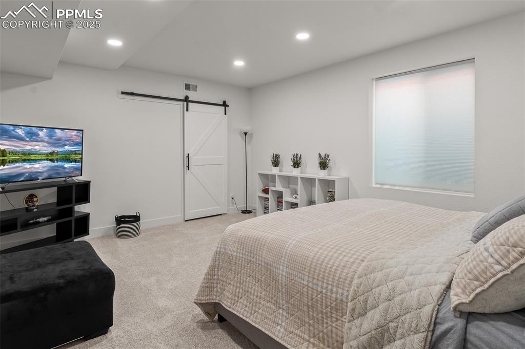 Image 43 of 48: Bedroom with carpet flooring, recessed lighting, and a barn door