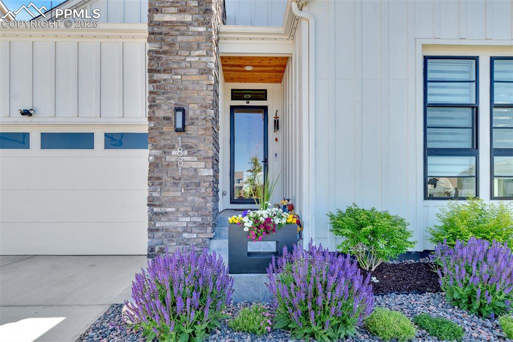 Image 7 of 48: Property entrance featuring board and batten siding, stone siding, and a ga