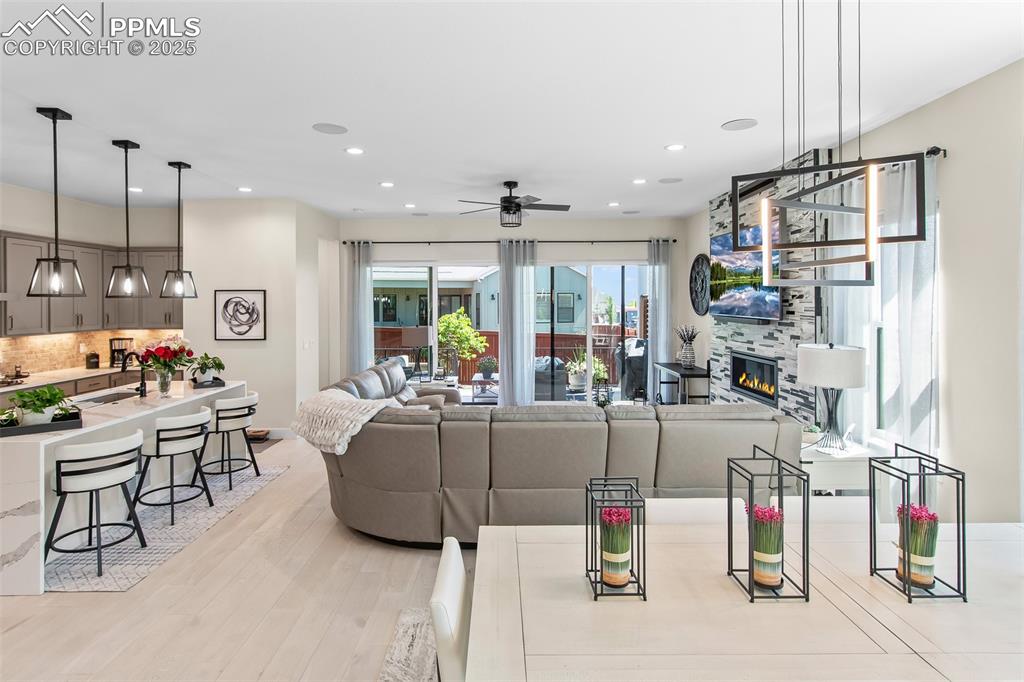Image 9 of 48: Living area featuring light wood-style floors, a fireplace, ceiling fan, an