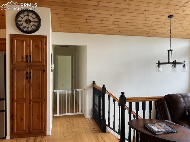 Image 18 of 39: Hallway with light wood-type flooring, an upstairs landing, baseboards, and