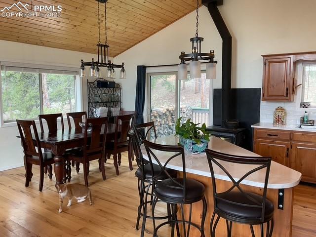 Image 25 of 39: Dining room with vaulted ceiling, a wood stove, light wood finished floors,