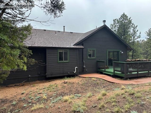 Image 4 of 39: Rear view of house with a wooden deck and a shingled roof