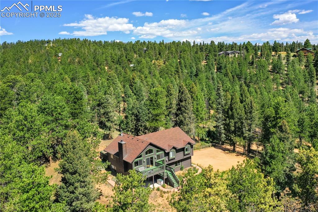 Image 8 of 39: Aerial view of property and surrounding area with a forest
