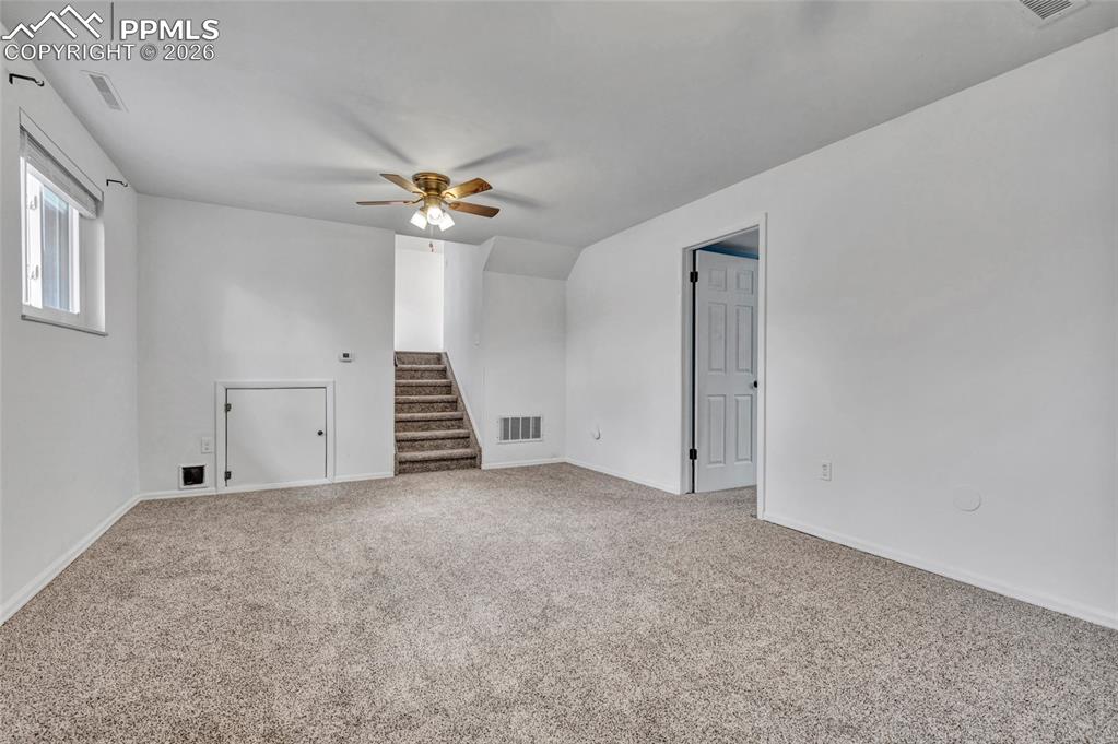 Image 28 of 31: Family room on lower level with gas fireplace, carpet, ceiling fans, and up