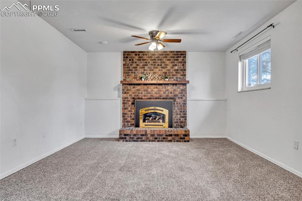 Image 6 of 31: Family room on lower level with gas fireplace, carpet, ceiling fans, and up