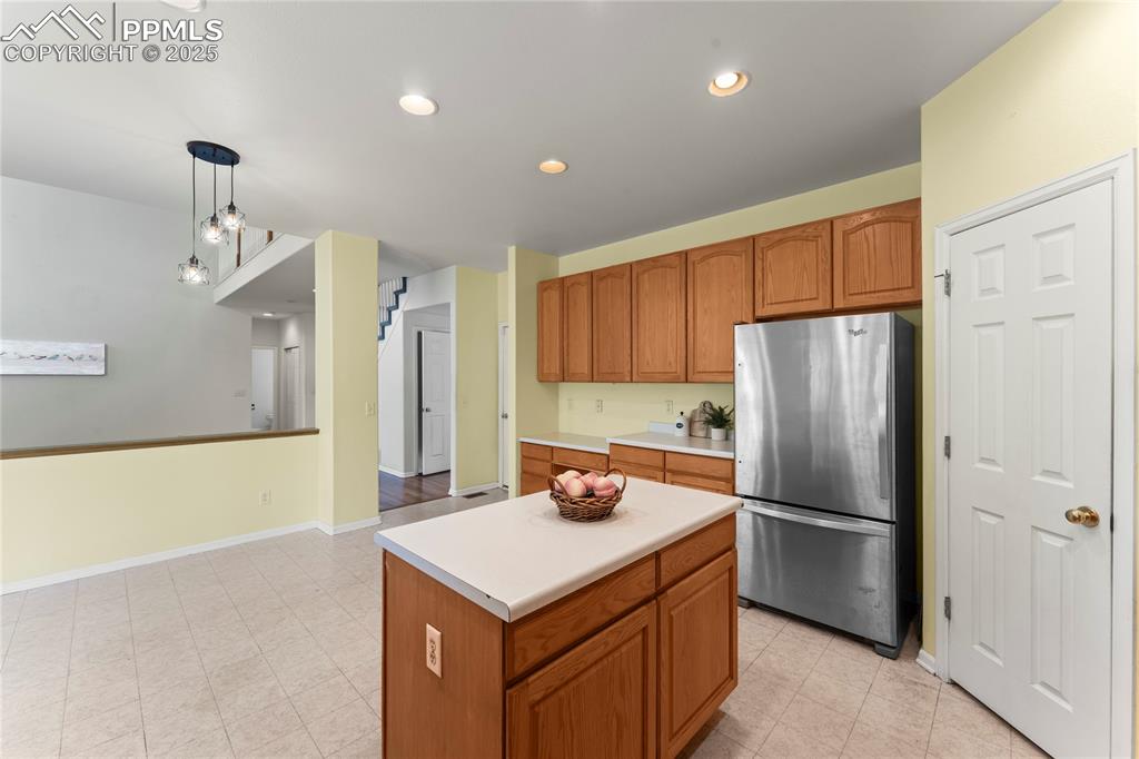 Image 18 of 49: Kitchen featuring freestanding refrigerator, pendant lighting, light counte