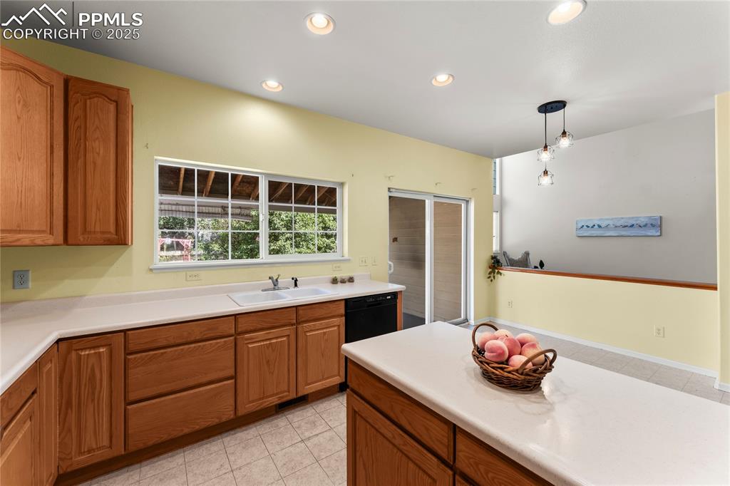 Image 19 of 49: Kitchen with light countertops, recessed lighting, brown cabinets, pendant 