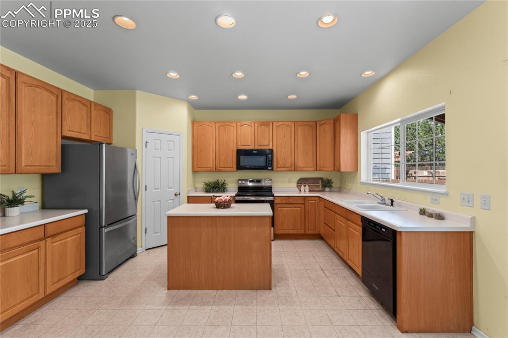 Image 6 of 49: Kitchen with light countertops, recessed lighting, black appliances, a cent