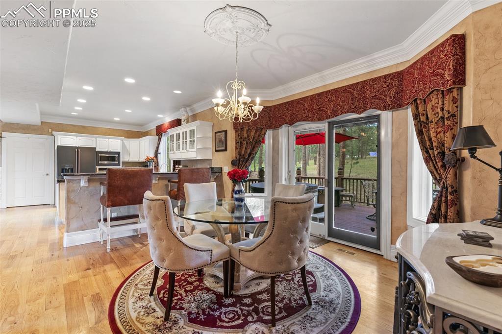 Image 11 of 50: Dining area with a chandelier, light wood-style floors, crown molding, and 