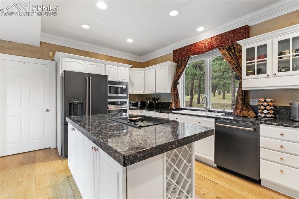 Image 13 of 50: Kitchen featuring black appliances, white cabinetry, a sink, glass insert c
