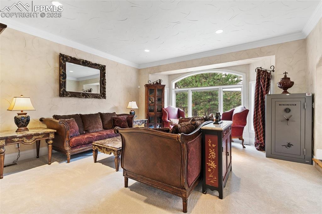 Image 17 of 50: Living area with light colored carpet, ornamental molding, and recessed lig