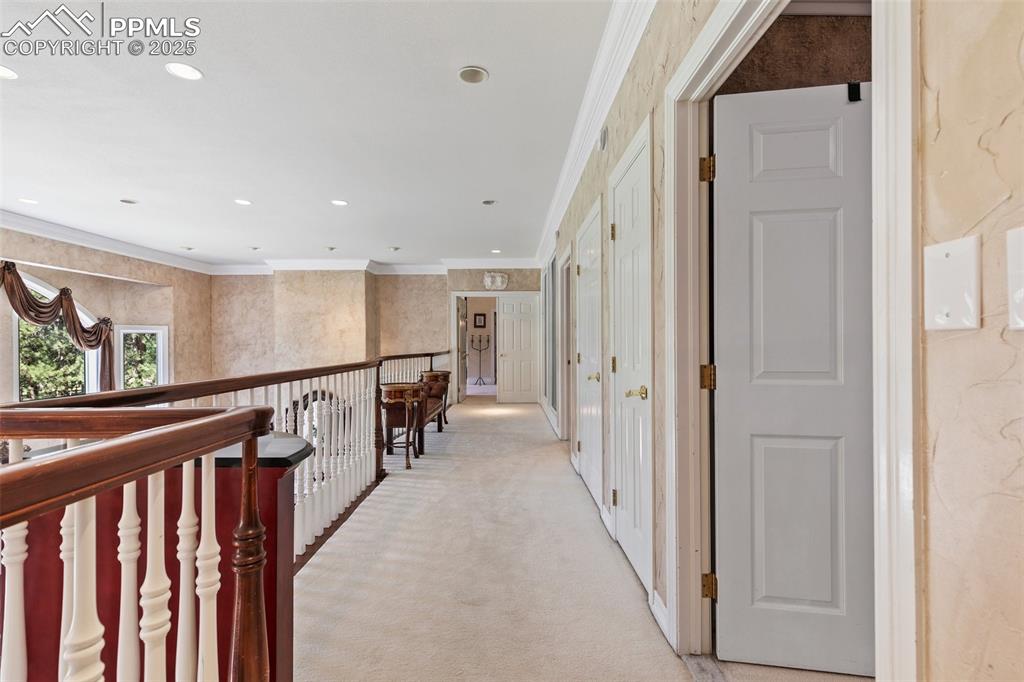 Image 22 of 50: Corridor with light carpet, crown molding, and recessed lighting