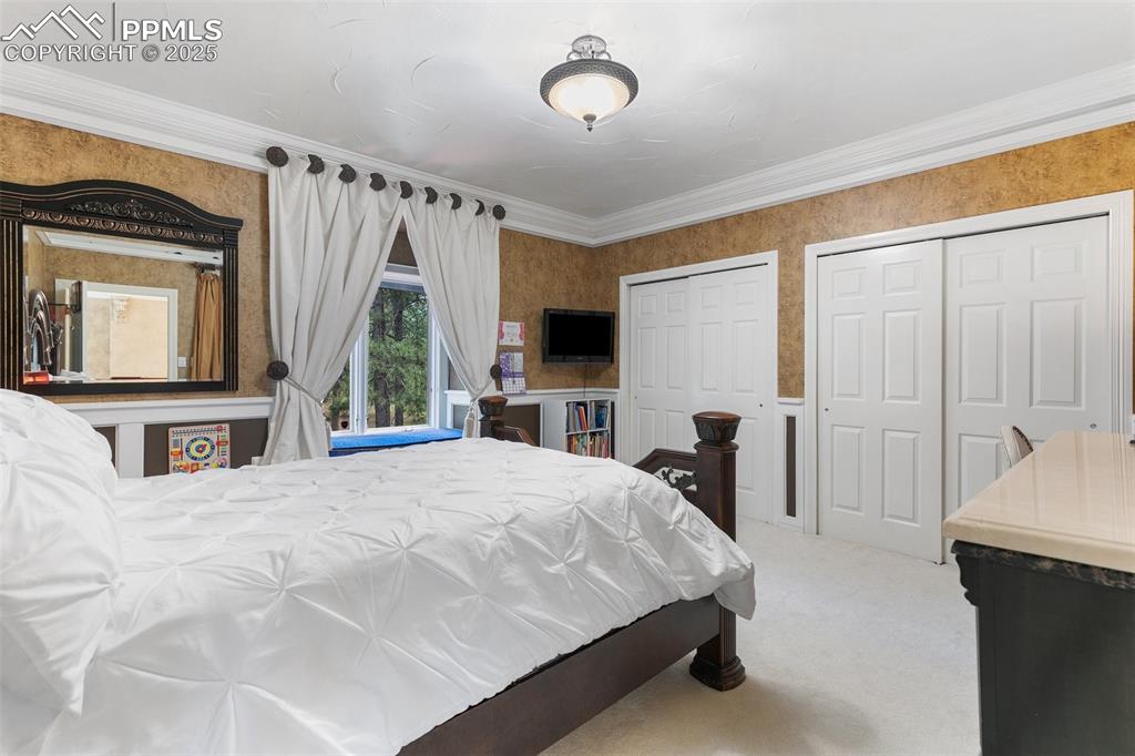 Image 23 of 50: Carpeted bedroom featuring two closets and crown molding