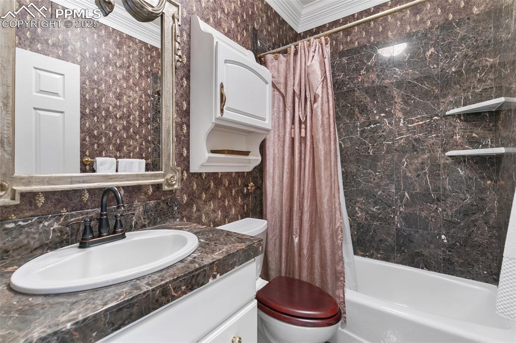 Image 25 of 50: Bathroom with toilet, vanity, shower / bath combo with shower curtain, and 