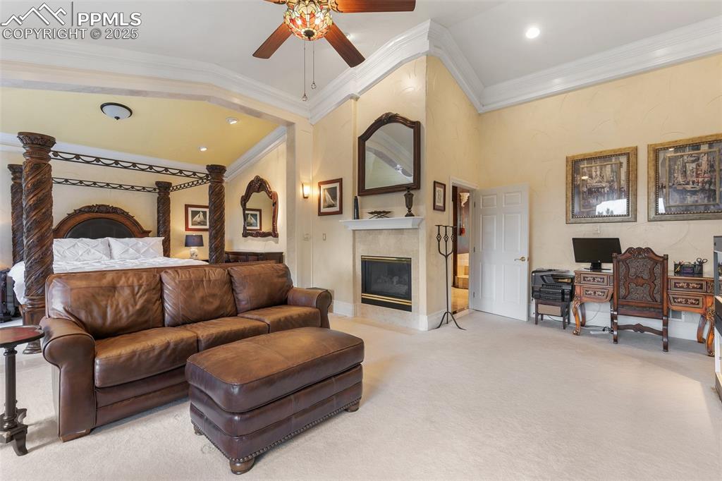 Image 29 of 50: Master bedroom with a ceiling fan, carpet flooring, a fireplace, crown mold