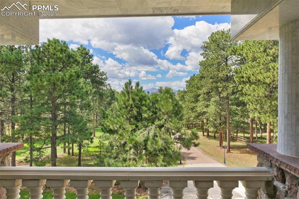 Image 31 of 50: Balcony with view of wooded area and breat taking views of Pikes Peak