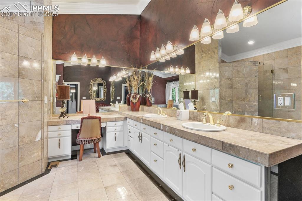 Image 33 of 50: Bathroom featuring crown molding, double vanity, tile walls, and tile patte