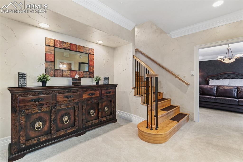 Image 35 of 50: Stairs featuring carpet flooring, ornamental molding, and a chandelier
