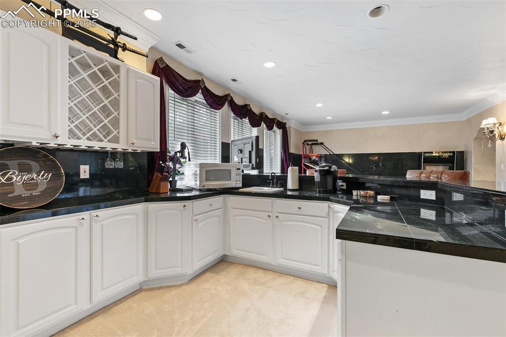 Image 38 of 50: Kitchen featuring a sink, white microwave, a peninsula, tasteful backsplash