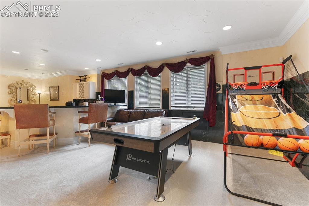 Image 40 of 50: Recreation room with crown molding, recessed lighting, and carpet