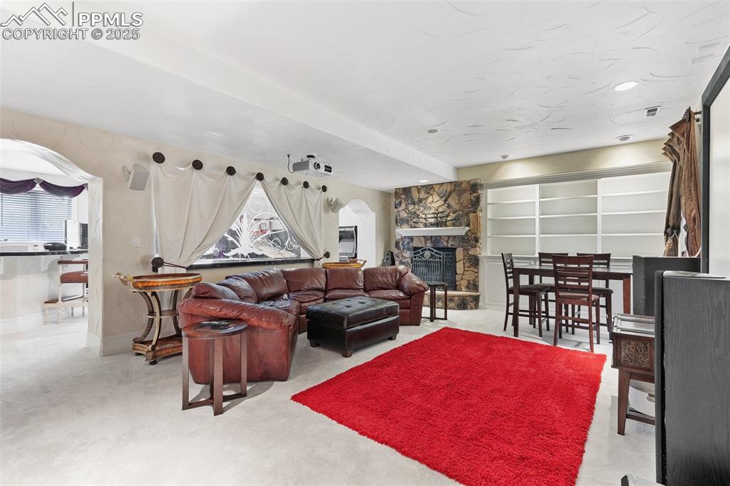 Image 43 of 50: Carpeted movie room with a fireplace and baseboards