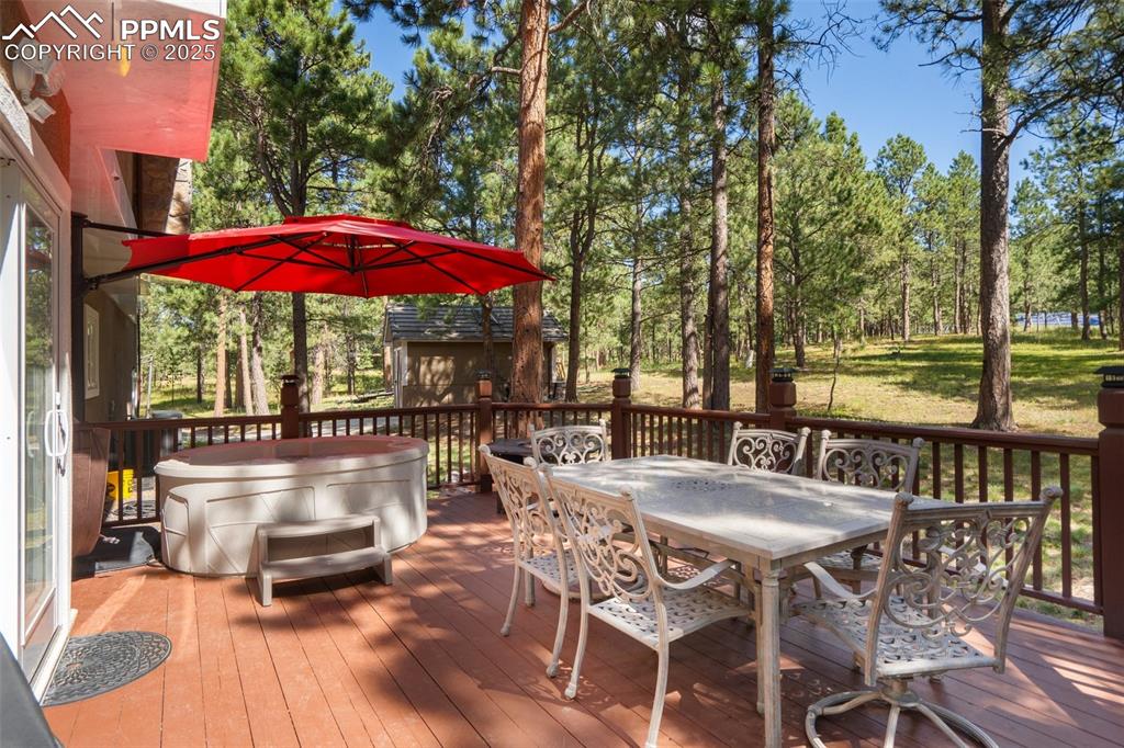 Image 46 of 50: Spacious deck featuring outdoor dining space, a hot tub, view of scattered 