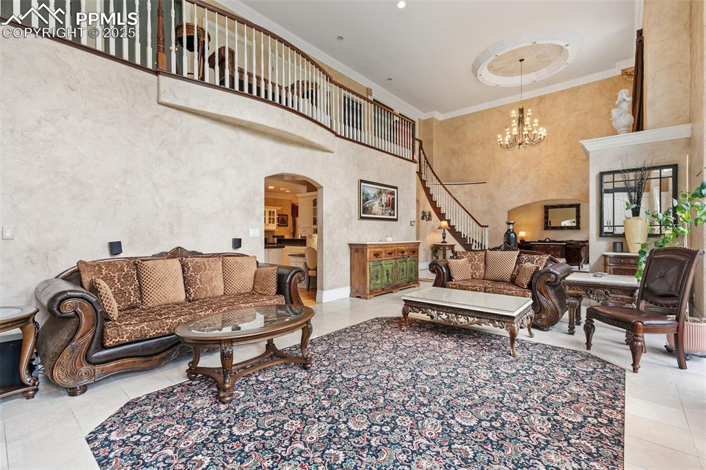 Image 8 of 50: Tiled living room featuring arched walkways, a high ceiling, a chandelier, 